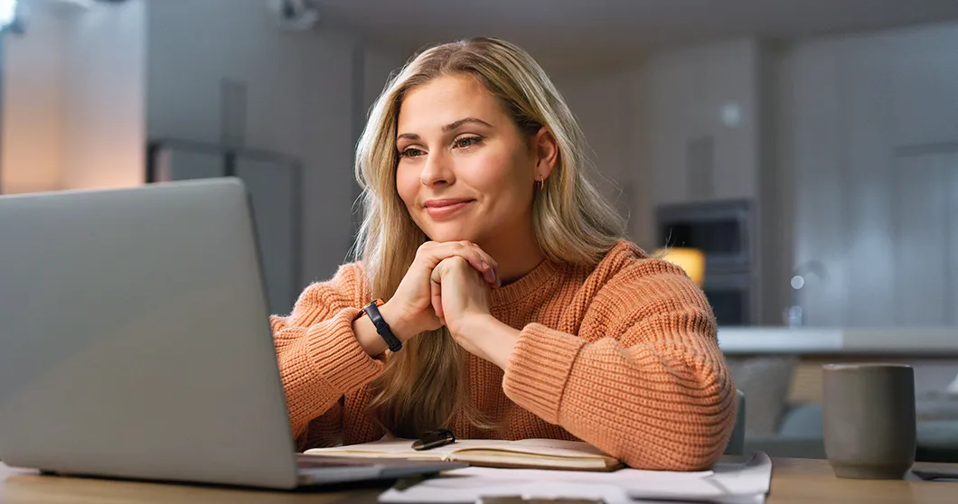 Mujer joven con mirada satisfecha viendo la pantalla del portátil